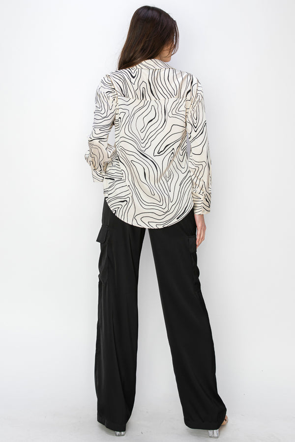 • SKU: T5384 • S-M-L (2-2-2) • Hand wash only • a long-sleeved shirt with a collar, featuring a print of black wavy lines connecting on a cream background. • This print resembles waves or undulating lines. • It's a versatile piece of women's clothing that would complement both dress pants and jeans. HIGH QUALITY & WHOLESALE PRICE W/ ONENMOREUSA.COM